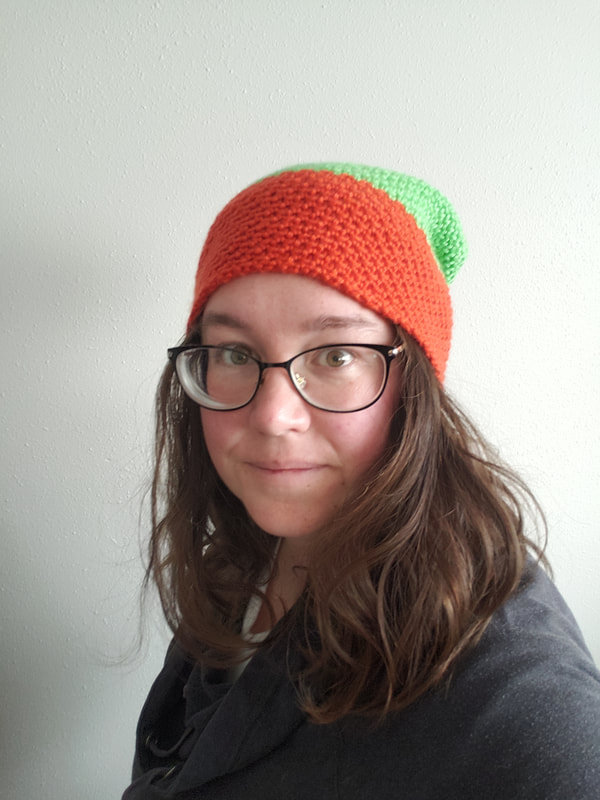 A woman wearing an orange and green crochet hat