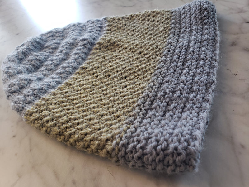 Gray and yellow knitted hat on marble background.