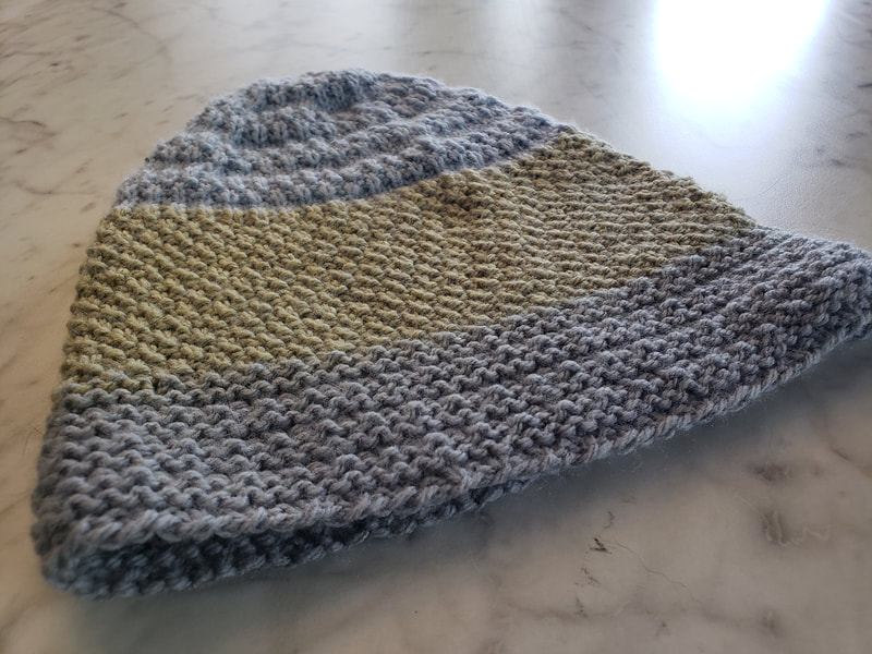 Gray and yellow knitted hat on a marble background.