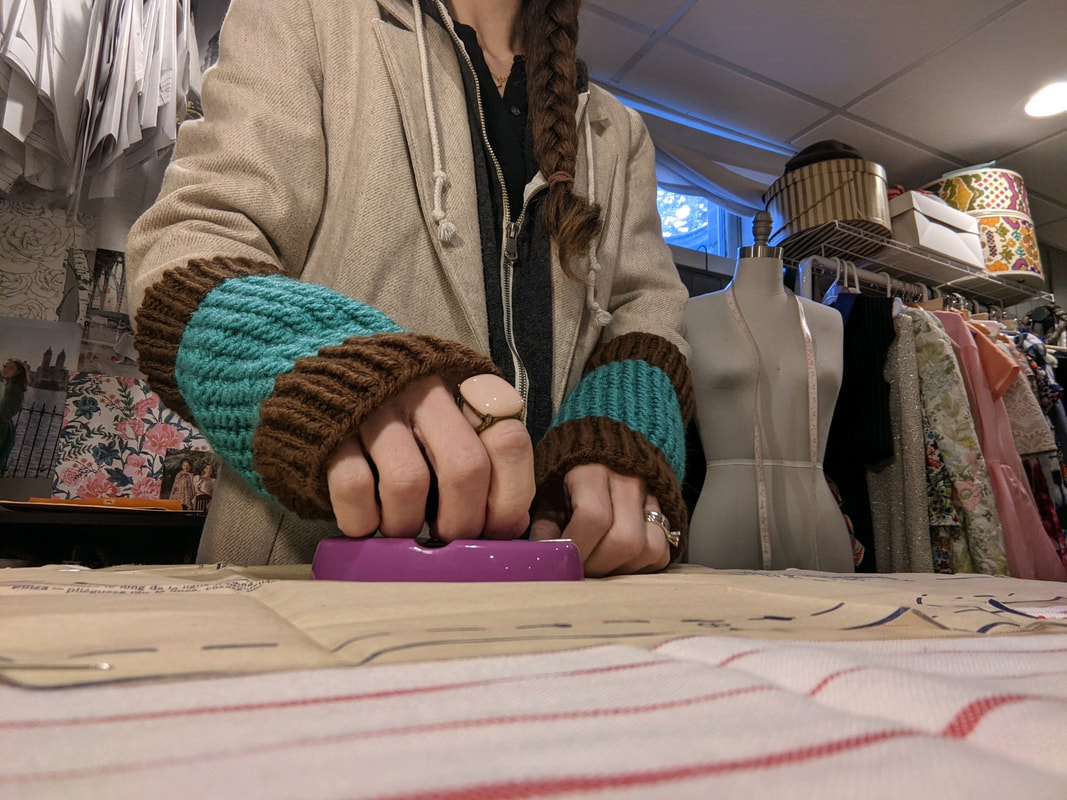 Woman wearing hand knitted wrist warmers with sewing materials in the background